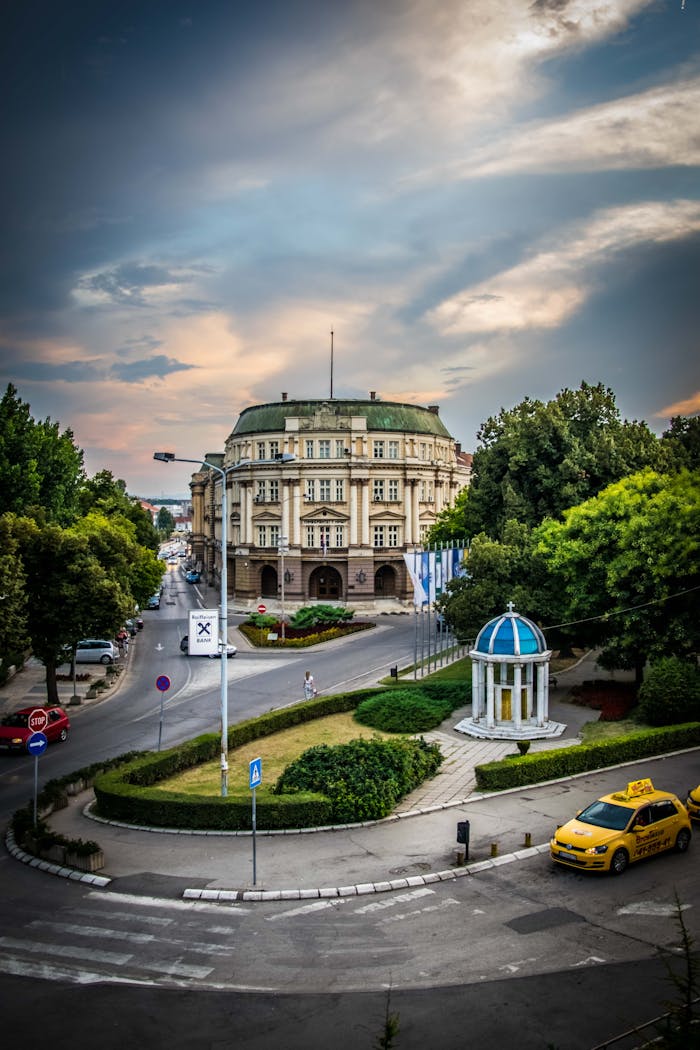 A historic building in Niš, Serbia, under a dramatic cloudy sky, showcasing elegant architecture.